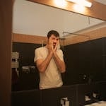 Tired man looking in mirror in bathroom